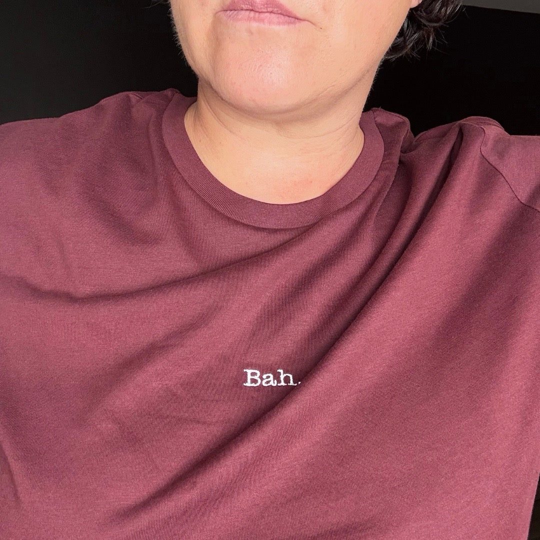 A dark cherry short-sleeve crewneck t-shirt with the word 'Bah.' A christmas t-shirt, women's relaxed fit t-shirt.