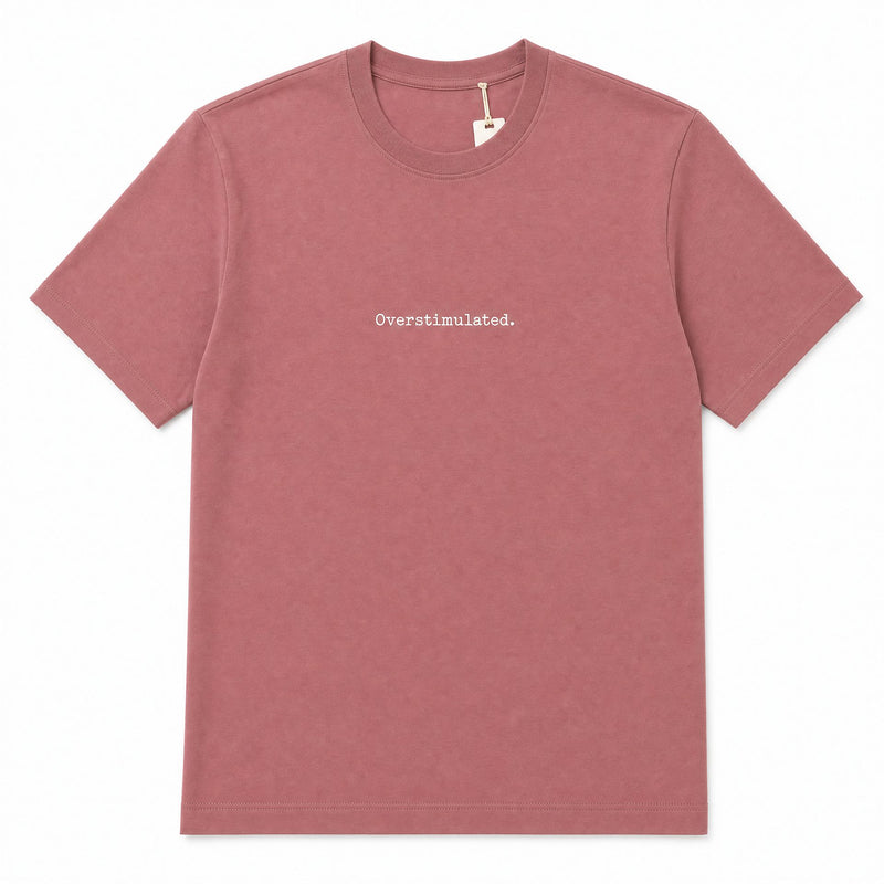 A dusty rose short-sleeve crewneck t-shirt with the word 'Overstimulated.' printed in white across the chest, displayed flat against a white background.