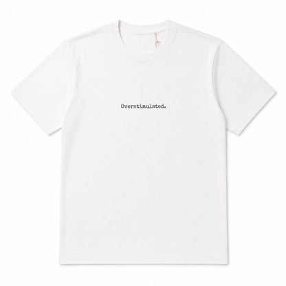 A white short-sleeve crewneck t-shirt with the word 'Overstimulated.' printed in a small black typewriter font at the center chest, displayed on a clean white background.