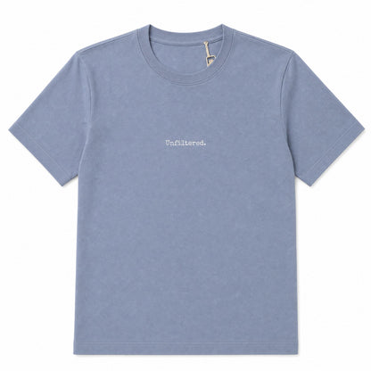 A light blue short-sleeve crewneck t-shirt with the word 'Unfiltered.' printed in white lowercase serif font on the center chest, displayed flat against a solid white background.