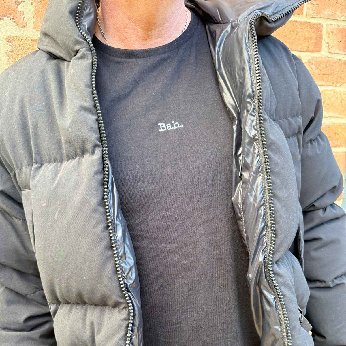 man in a coat wearing a black christmas t-shirt that says Bah,.