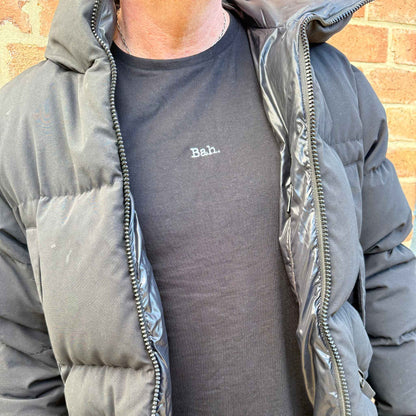 man in a coat wearing a black christmas t-shirt that says Bah,.