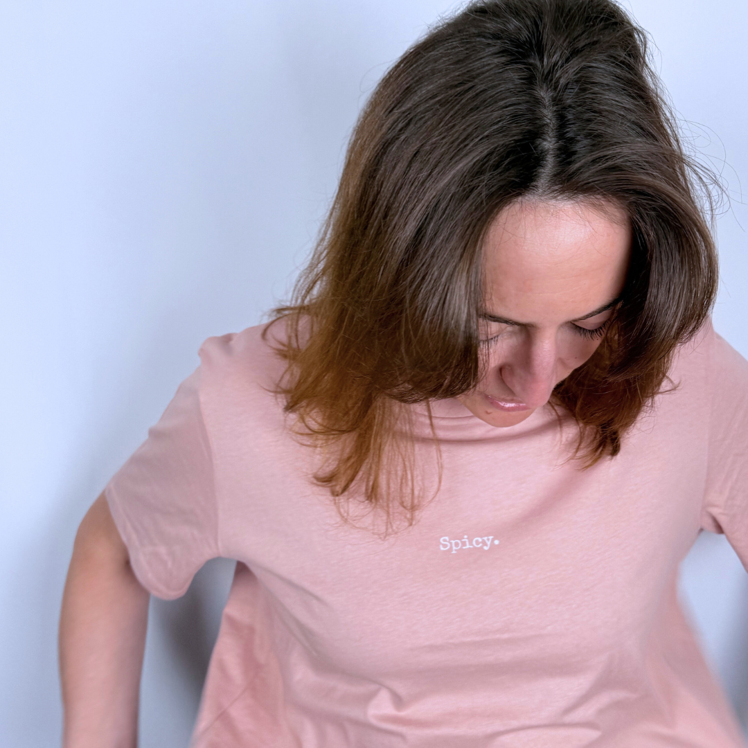 Woman wearing a pink t-shirt with 'Spicy' text on a light blue background