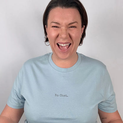 Person wearing a light blue t-shirt with 'No Chat.' text on a plain background