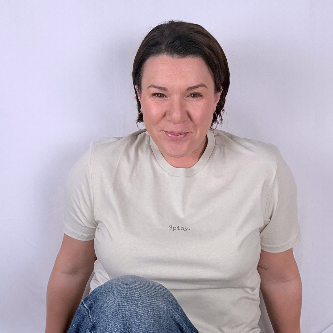 Woman wearing a beige t-shirt with 'Spicy' text against a white background