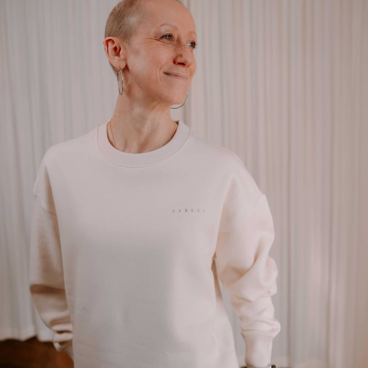 Person wearing a white sweatshirt with text against a neutral background