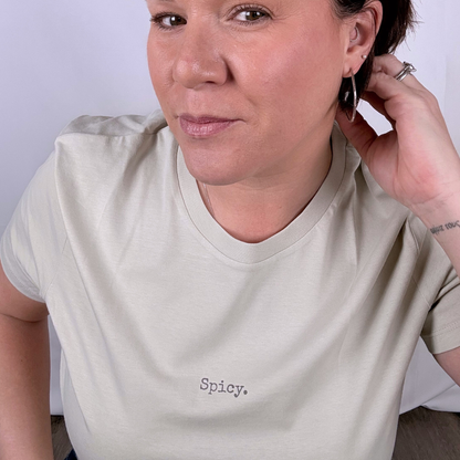 Woman wearing a beige t-shirt with 'Spicy' text on a plain background