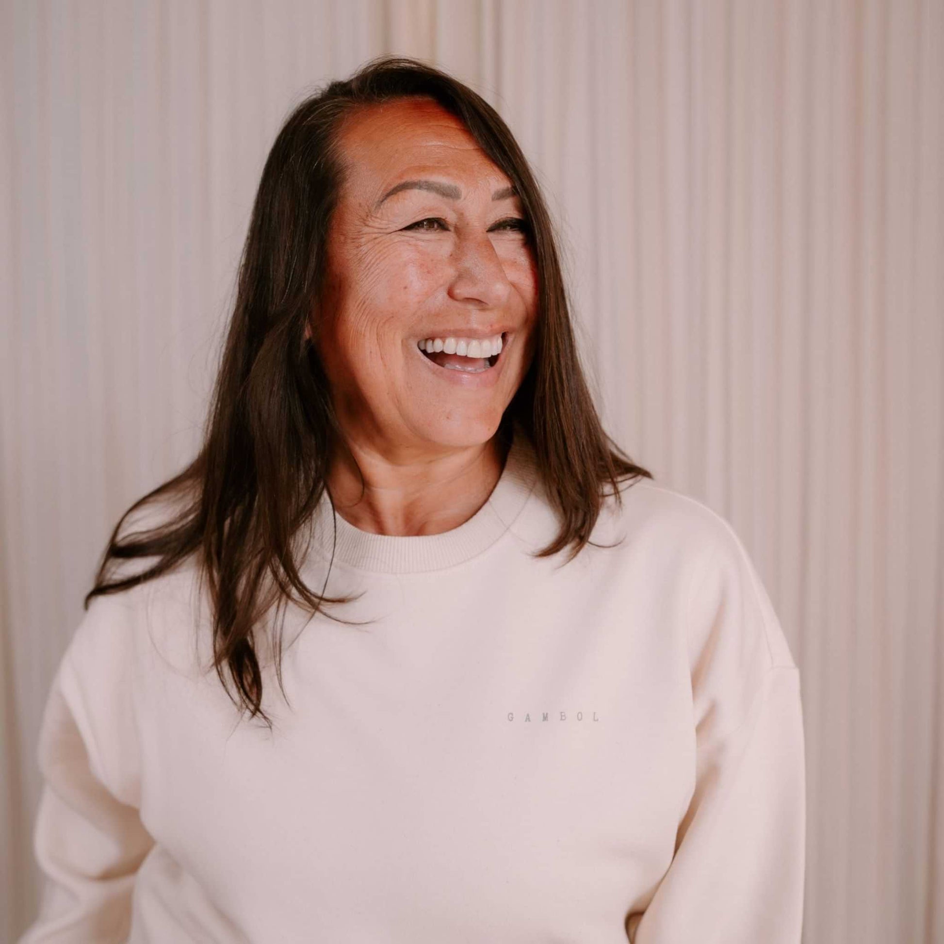 Woman wearing a light-colored sweater with a subtle pattern in the background