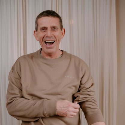 Man wearing a beige sweatshirt against a neutral background