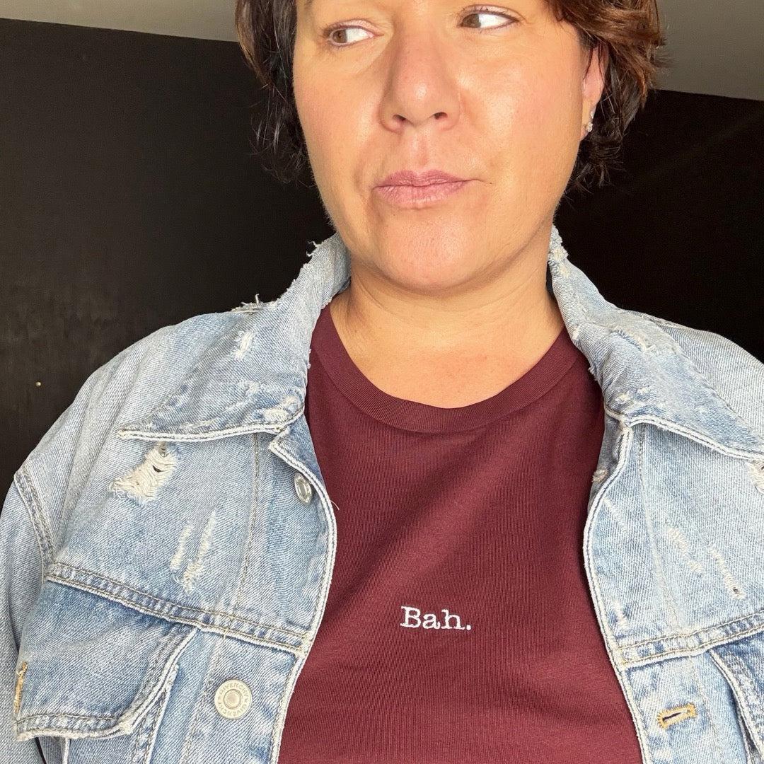 A dark cherry short-sleeve crewneck t-shirt with the word 'Bah.' A christmas t-shirt, women's relaxed fit t-shirt.