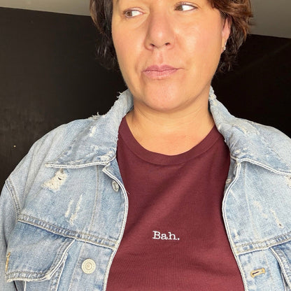 A dark cherry short-sleeve crewneck t-shirt with the word 'Bah.' A christmas t-shirt, women's relaxed fit t-shirt.