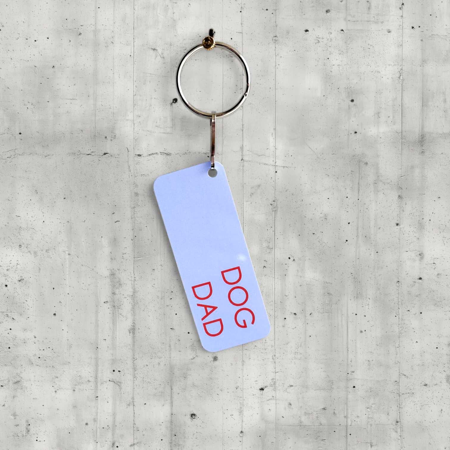Keychain with 'DOG DAD' text on a concrete surface