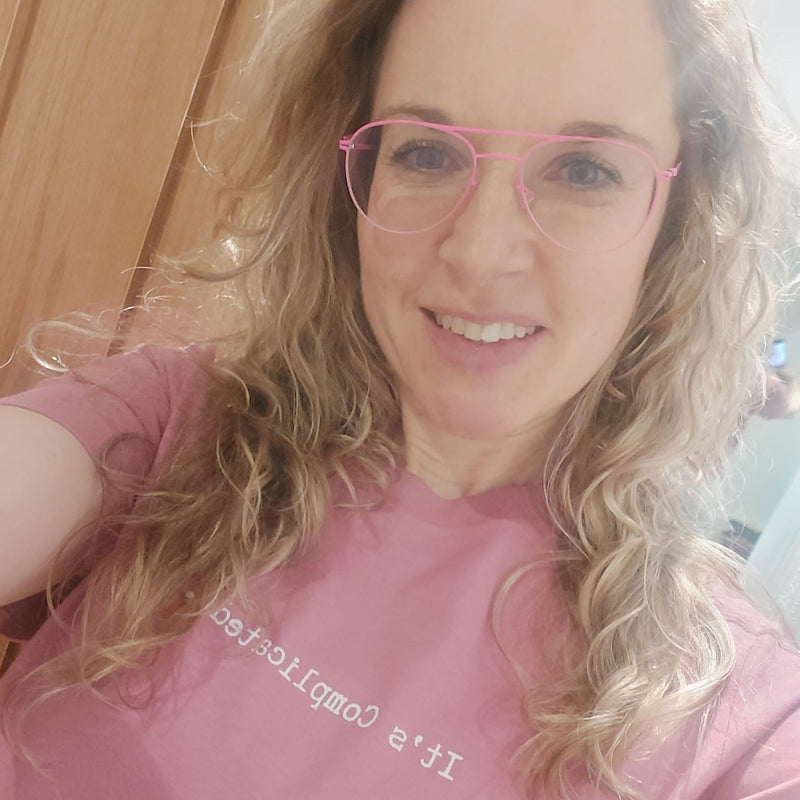 Woman wearing a pink shirt with text saying Spicy, smiling .