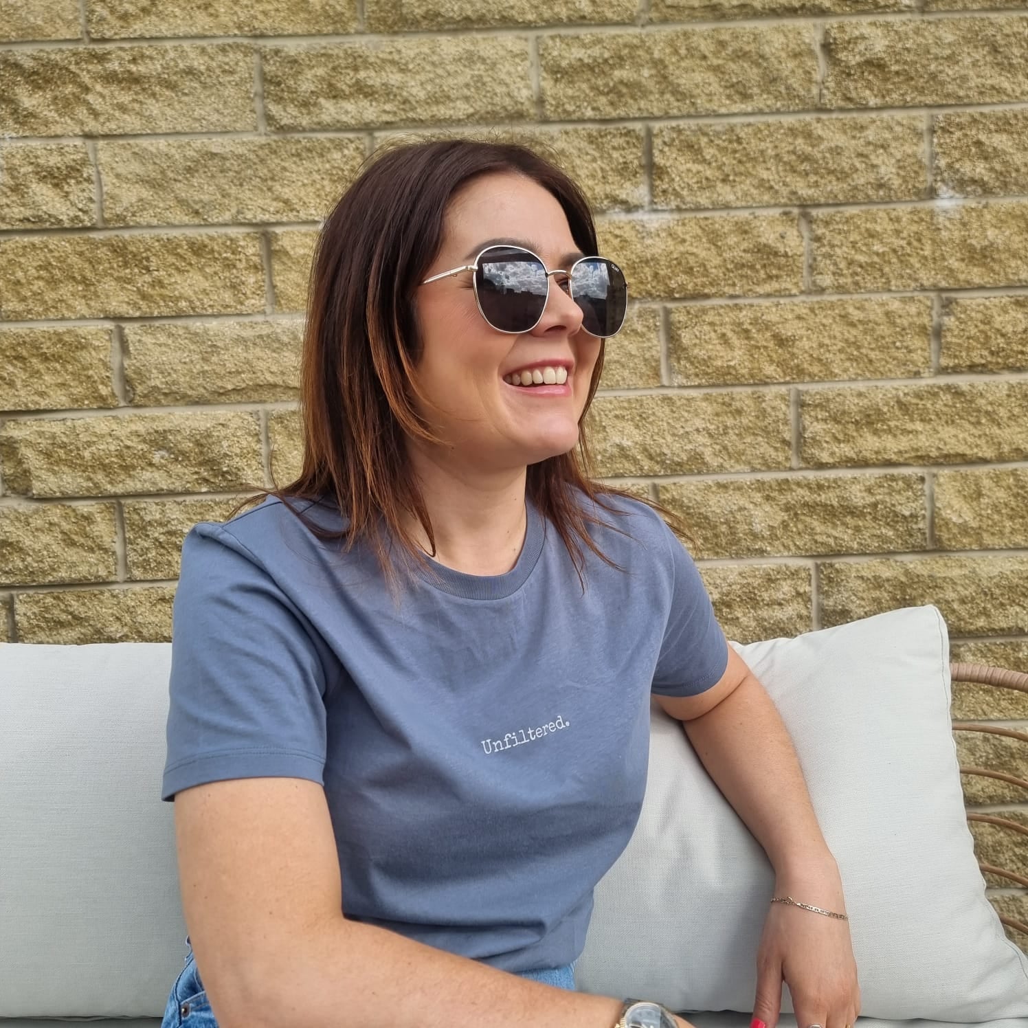 woman wearing grey t-shirt that says unfiltered with sunglasses and smiling