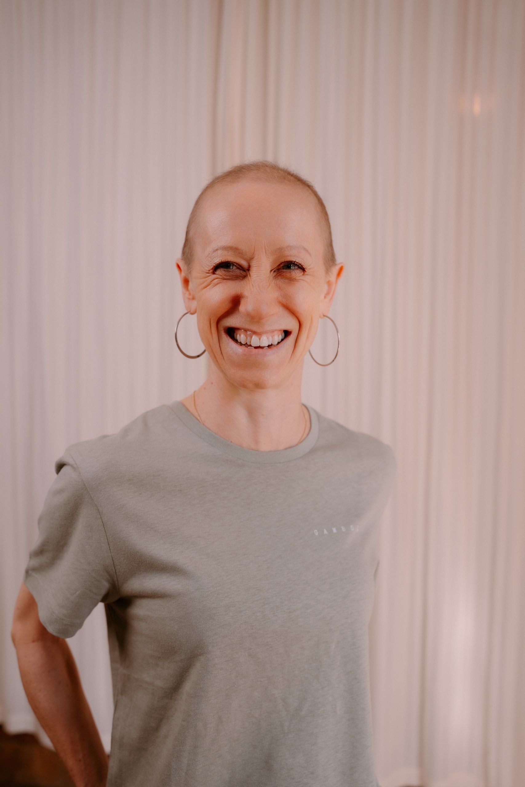 Person wearing a gray t-shirt with a subtle design, standing against a neutral background