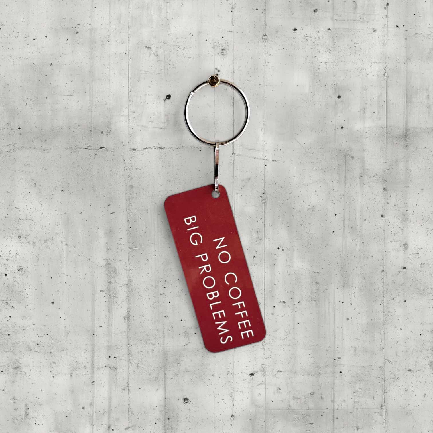 Red keychain with 'No Coffee Big Problems' text on a concrete surface