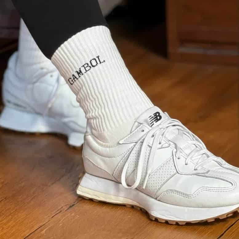 White sneakers and socks with 'Gambol' branding on a wooden floor.