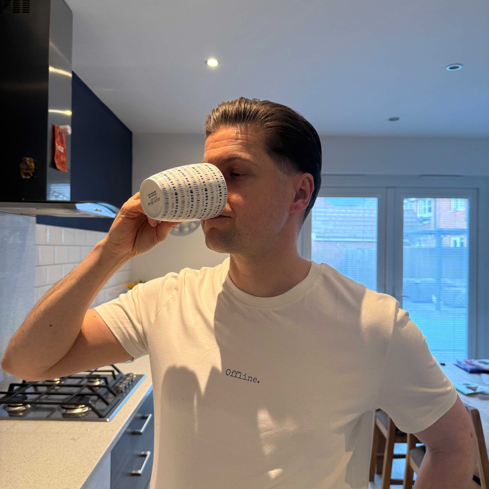 Man drinking from a coffee cup in a kitchen