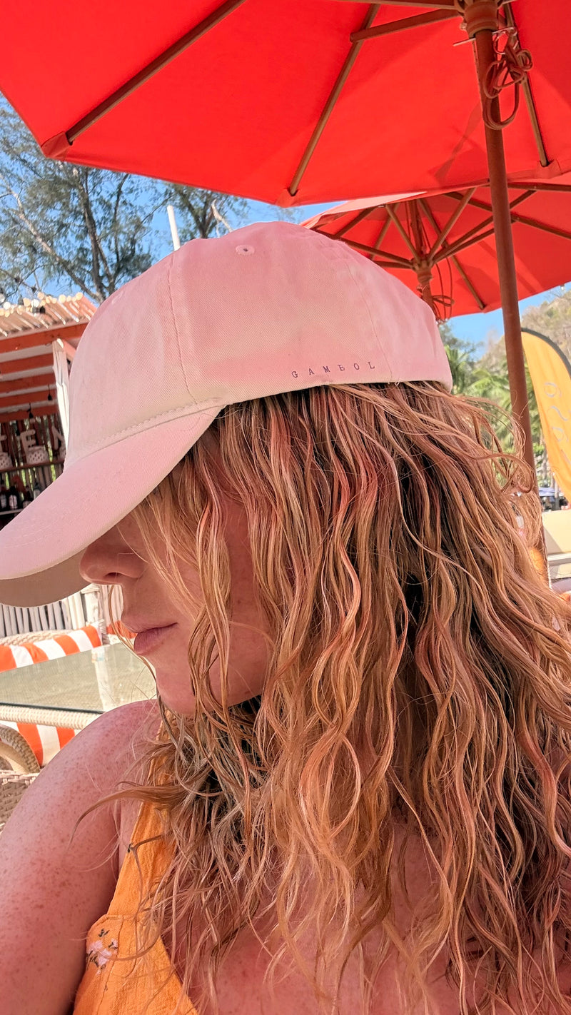 Person wearing a pink cap under a red umbrella with a blurred background