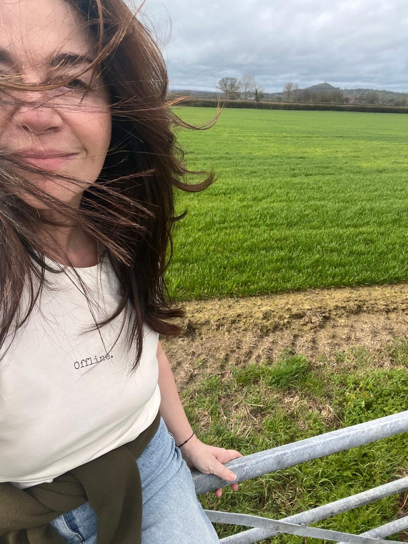 Person standing in front of a green field with a cloudy sky