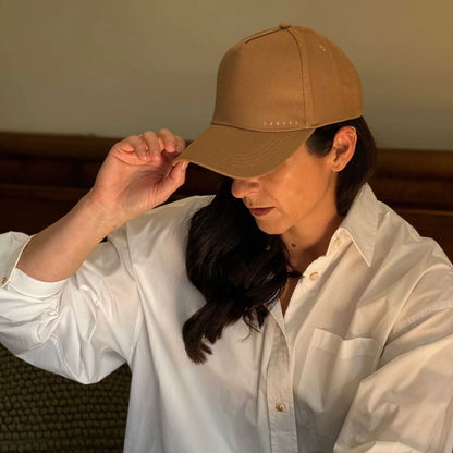 Person wearing a brown cap and white shirt indoors