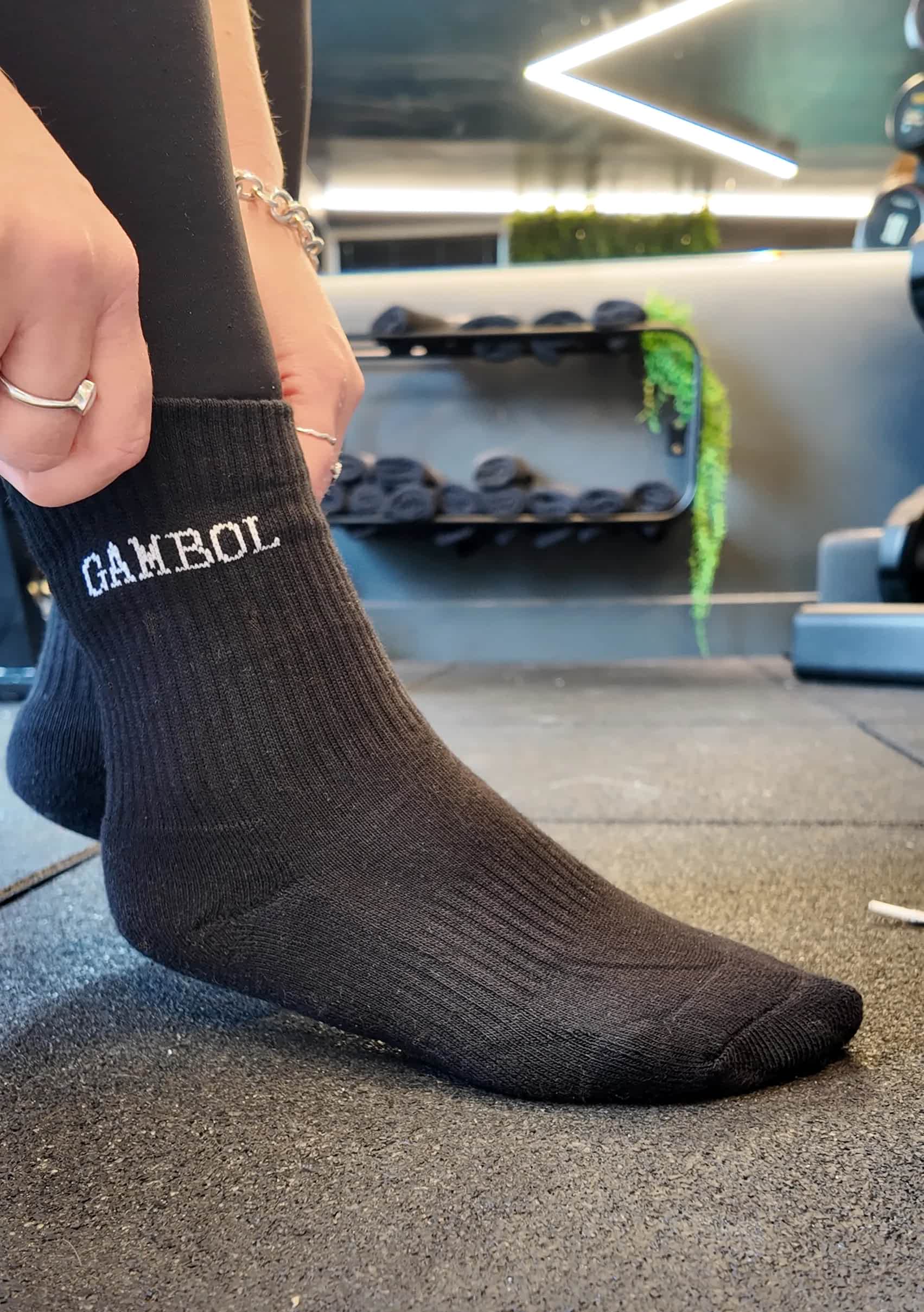 Person wearing black socks with 'Gambol' branding in a gym setting