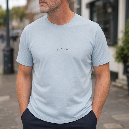 Man wearing a light blue t-shirt with 'No Chat.' text on a street background