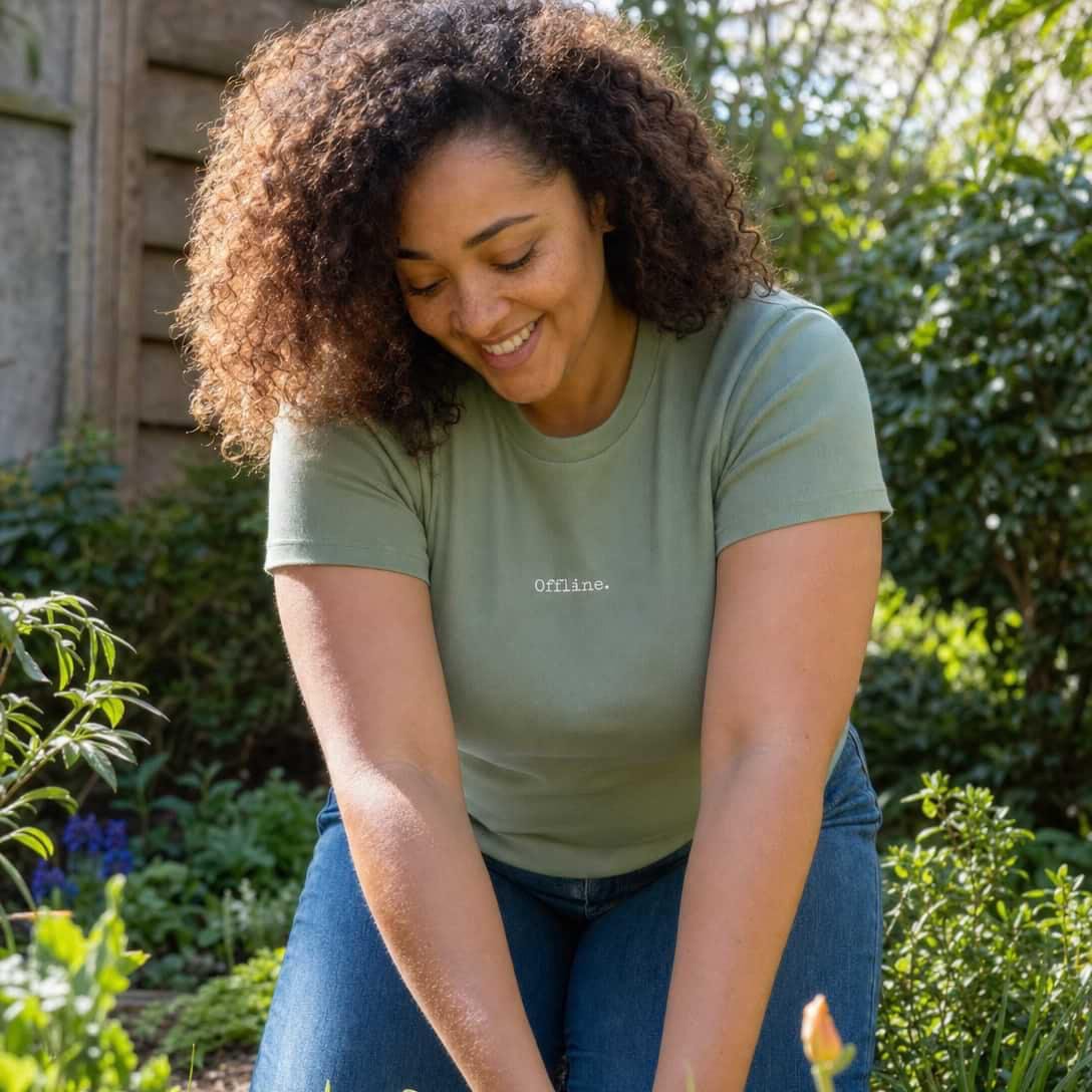 Woman gardening in a lush garden wearing a green shirt with 'Smith' printed on it.