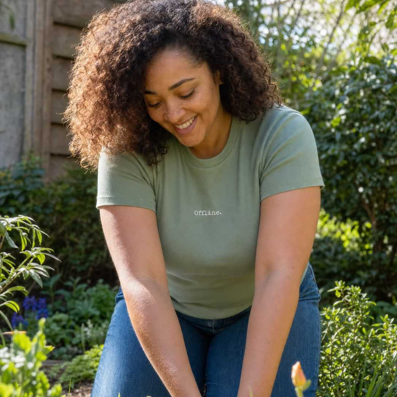 Woman gardening in a lush garden wearing a green shirt with 'Smith' printed on it.