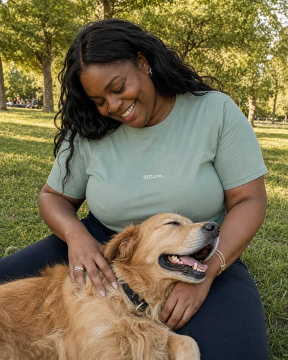 Woman sitting on grass with a dog, both smiling outdoors