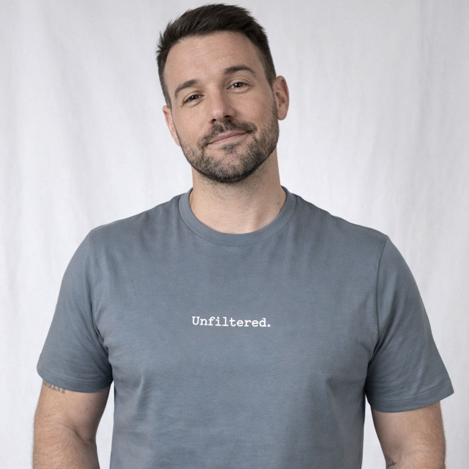 Man wearing a gray t-shirt with 'Unfiltered.' text on a plain background