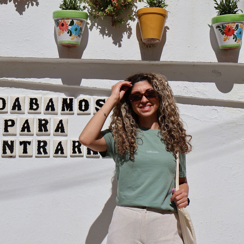 Woman posing in front of a white wall with decorative pots and a sign.